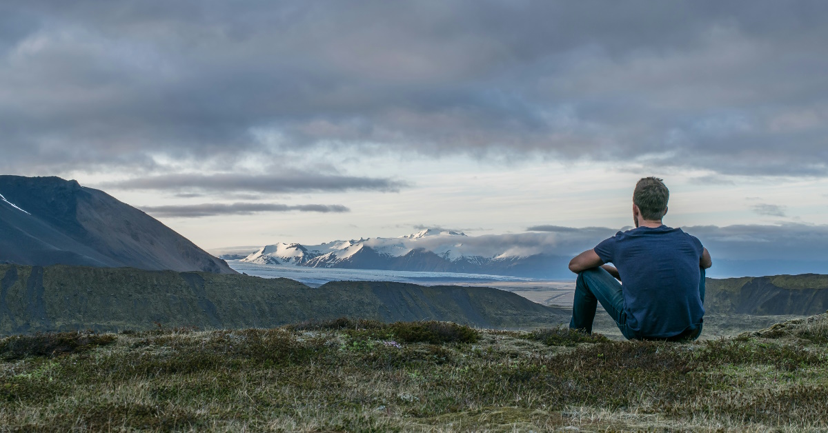 Mann i naturen som føler på stress og ser ut over landskapet