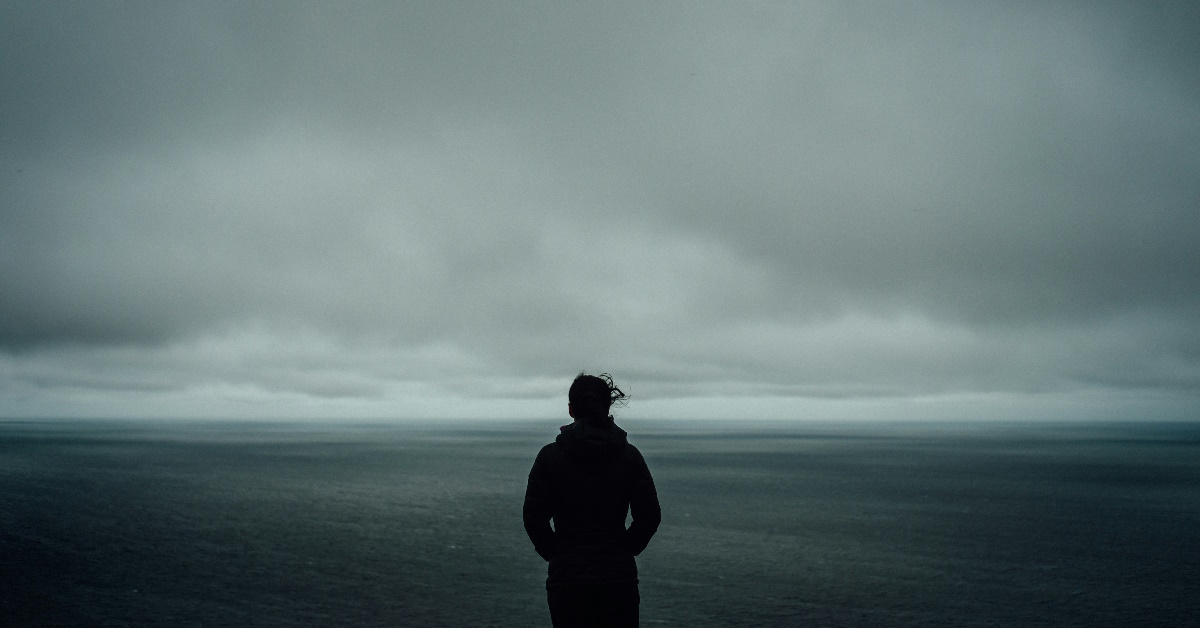 Person som føler seg utbrent ute i grå natur.